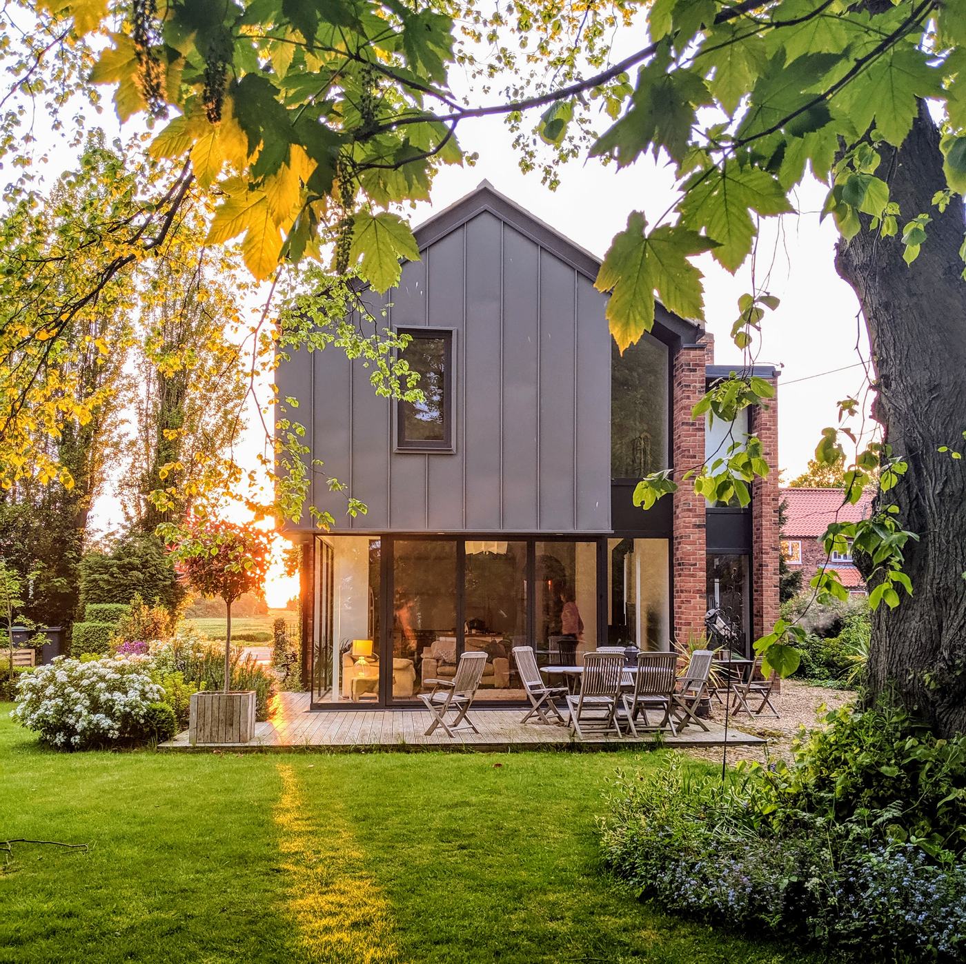 Completed zinc-clad home with brick chimney at sunset