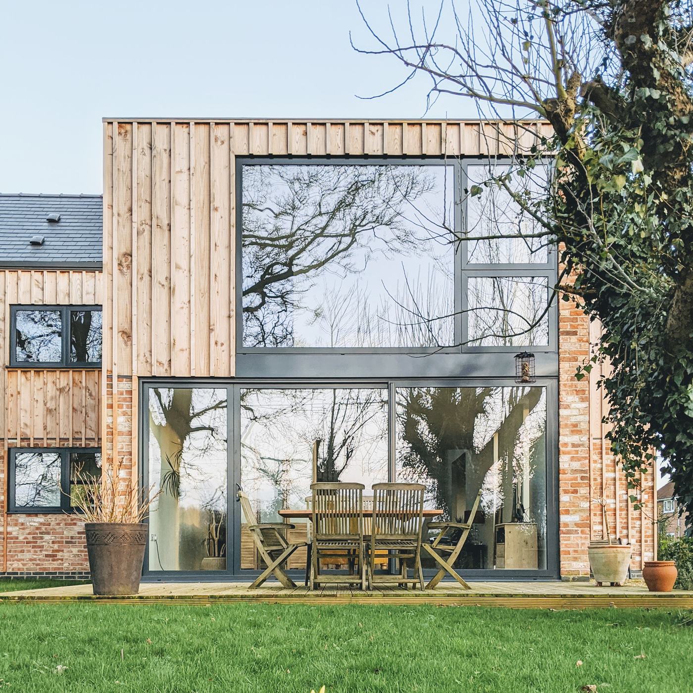 Garden elevation of a completed timber and brick home with full-height glazing